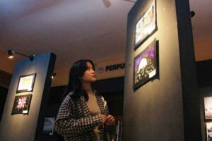 Salah seorang pengunjung saat melihat karya fotografi alternatif karya mahasiswa Unitomo yang tergabung di CIPHOC, dalam acara Dies Natalis CIPHOC ke 30, di Gedung F Lantai 1 Unitomo
