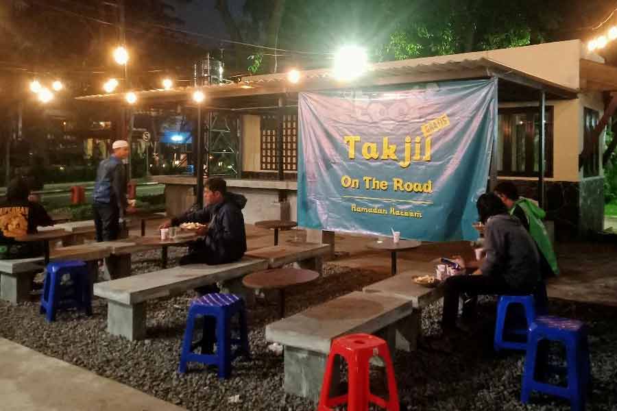 Para pengguna jalan saat menyantap menu buka makan di tempat yang dibagikan komunitas Awoiwoi di Taman Ngagel, Surabaya, Minggu (16/4/2023) 