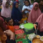 Warga mengantri untuk bisa menikmati menu ketupat, saat digelar tradisi kupatan di Kampung Sukolilo Surabaya. (foto: Anton Kusnanto, pilar.id)