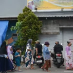 Warga yang sudah mendapatkan menu ketupat, segera mencari tempat untuk bisa menyantap. (foto: Anton Kusnanto, pilar.id)