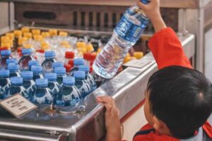 Tumbuh Pesat, Bisnis AMDK Diproyeksi Naik 25,5 Persen Lima tahun ke Depan Anak kecil mengambil satu botol air minum dalam kemasan (foto: Adam Navarro, unsplash)