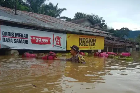 Petugas Bhabinkamtibmas Polsek Air Besar saat berupaya menerjang banjir untuk melakukan evakuasi warga terdampak banjir bandang (foto: Dok Humas Polri)