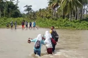Bripka Muhamad Syahril Watiwa saat menyeberangkan pelajar (foto: Dok Humas Polri)