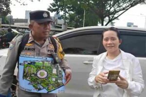 Aiptu Kamidi, anggota Bhabinkamtibmas Polsek Metro Menteng, mengalungkan denah Stadion Utama Gelora Bung Karno untuk memudahkan pengunjung di lokasi. (foto: Dok Humas Polri)