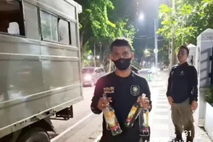 Anggota Satpol PP Surabaya menunjukkan bukti botol miras usai Operasi Yustisi di kawasan Jembatan Suramadu